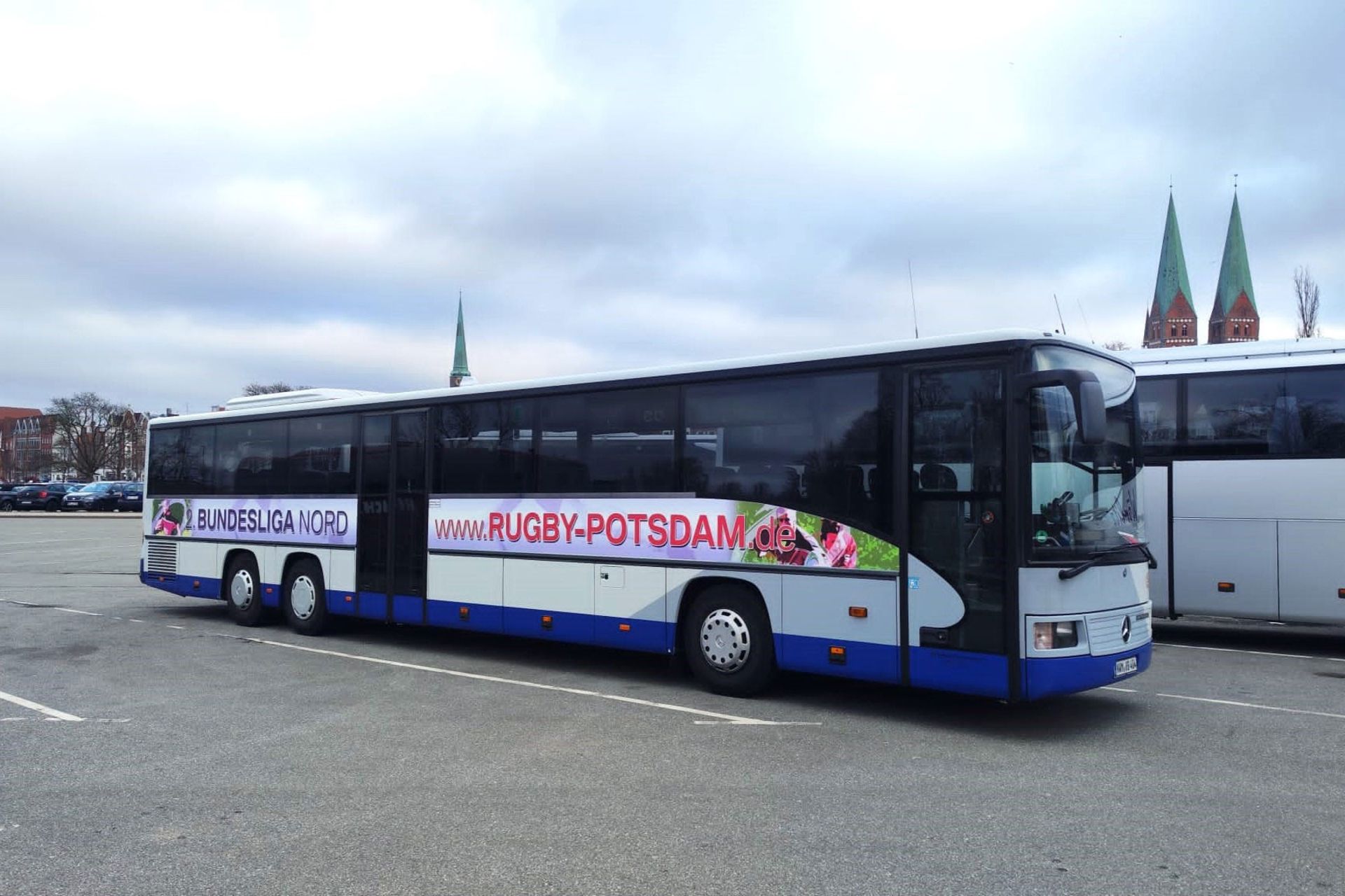 Ein weiß-blauer Bus steht auf der Straße, bereit zur Abfahrt.