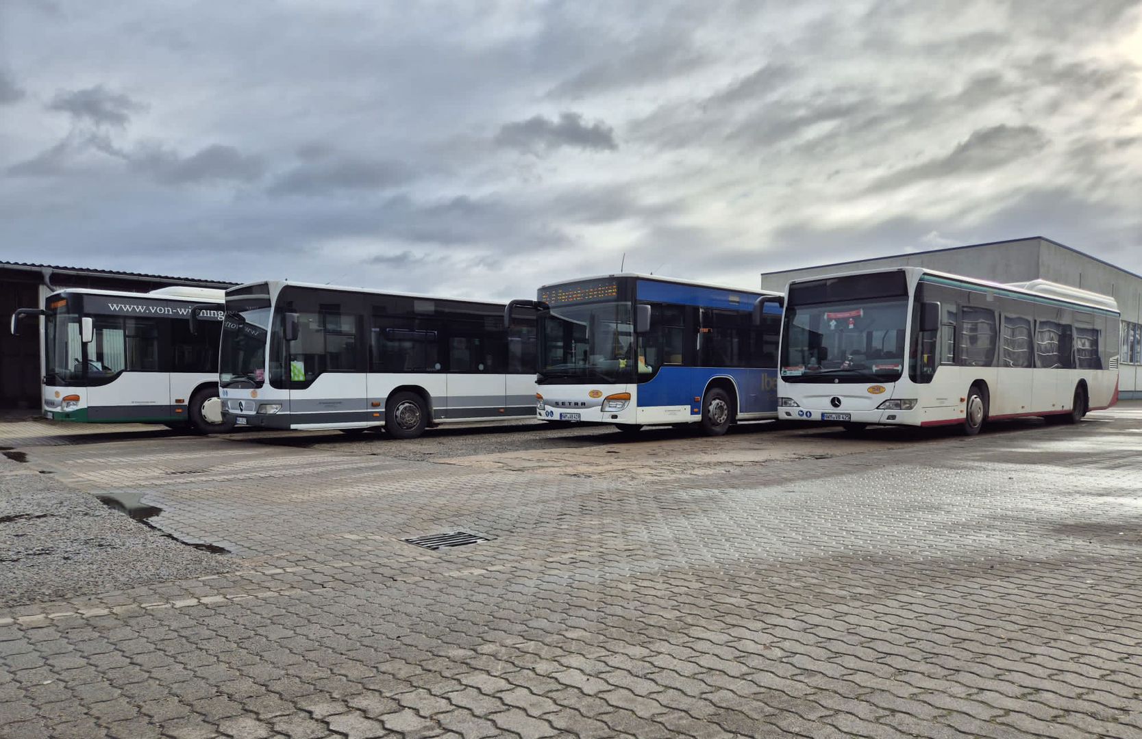 Mehrere Busse stehen in einer Reihe auf einem Parkplatz, bereit für Busreisen.